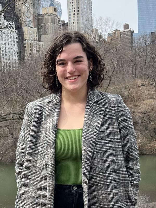 Alex Ensign standing in front of city buildings, river,