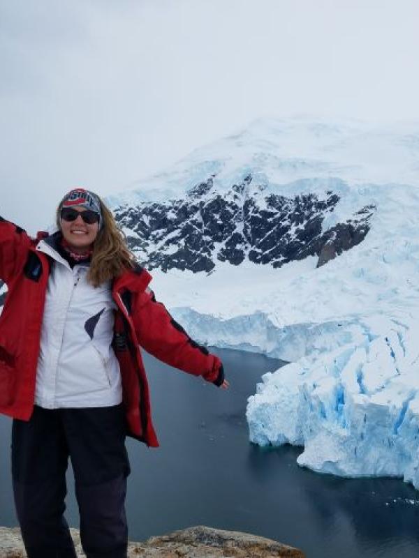 Karina Peggau posing in front of glacier wearing a red jacket