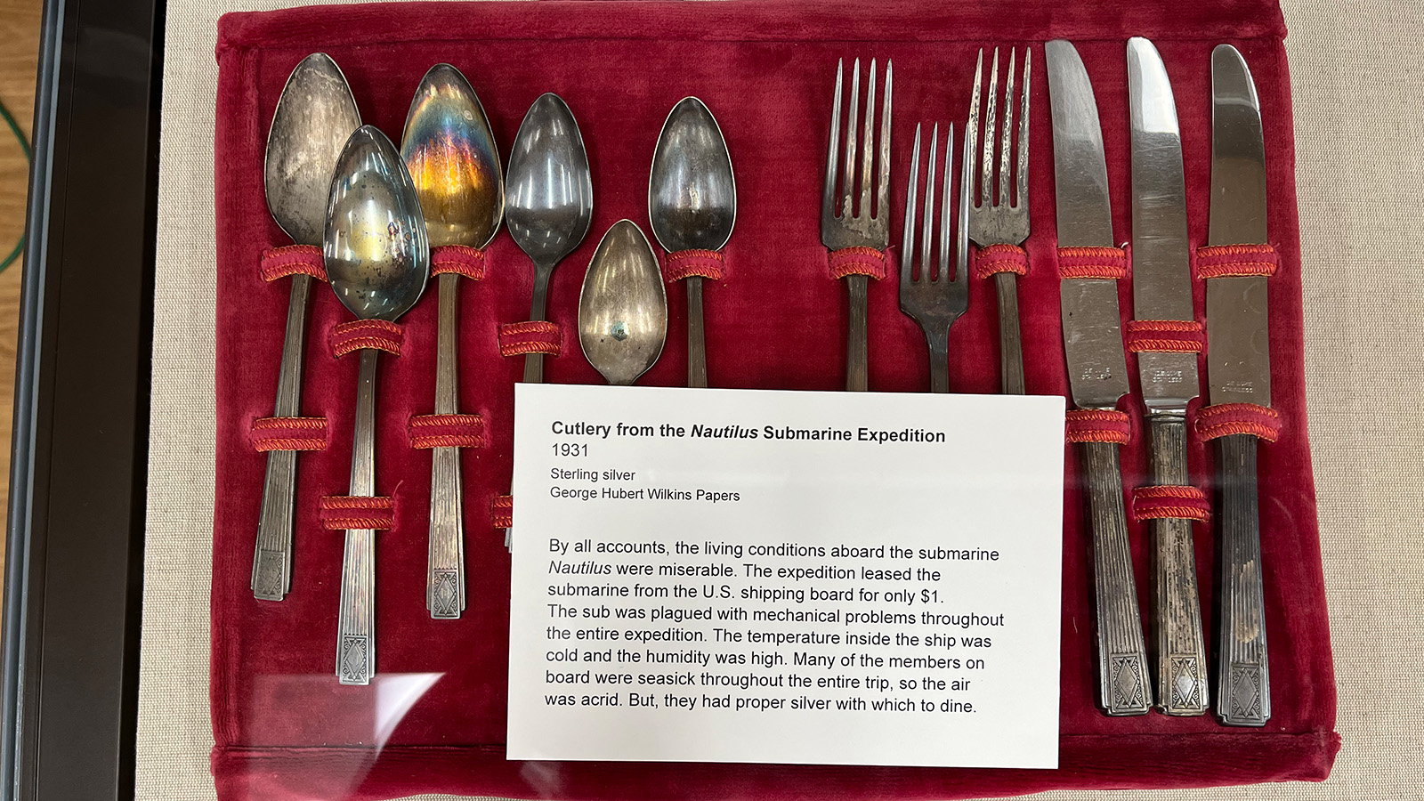 Silver cutlery from the Nautilus. The silverware lays neatly in a red holder 