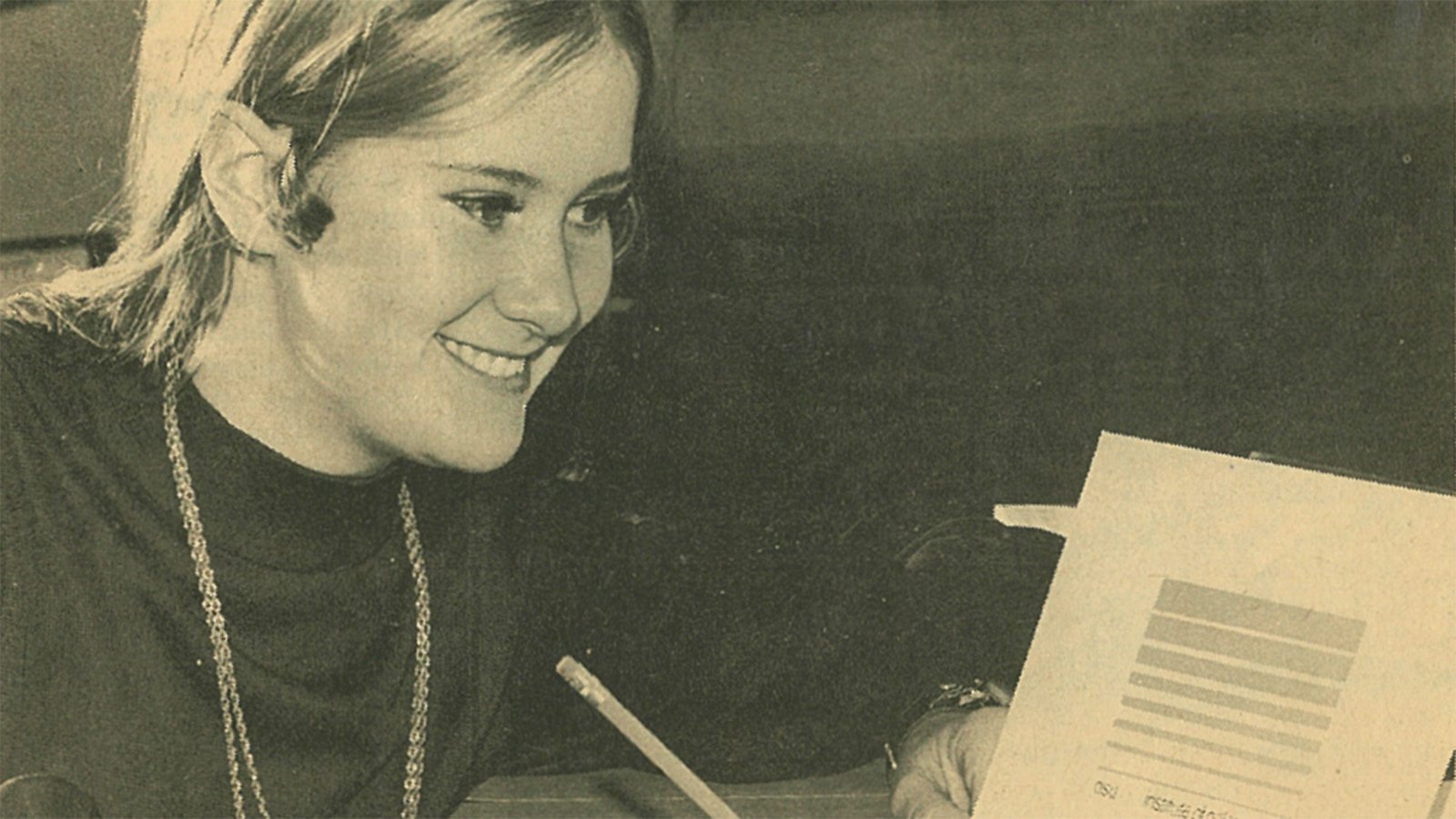 A black-and-white photograph of a young Susannah Casey holding a picture of her design for the Byrd Center's flag