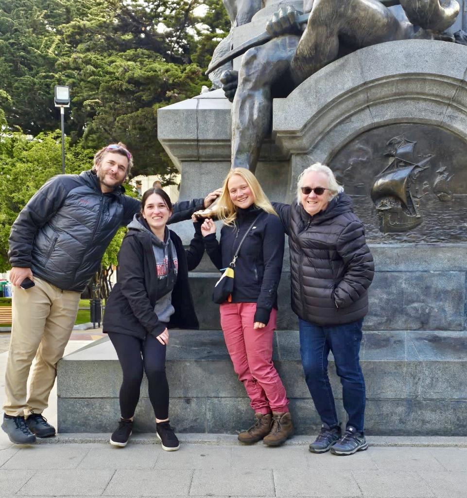 Four people posing in front of the base of a statute.