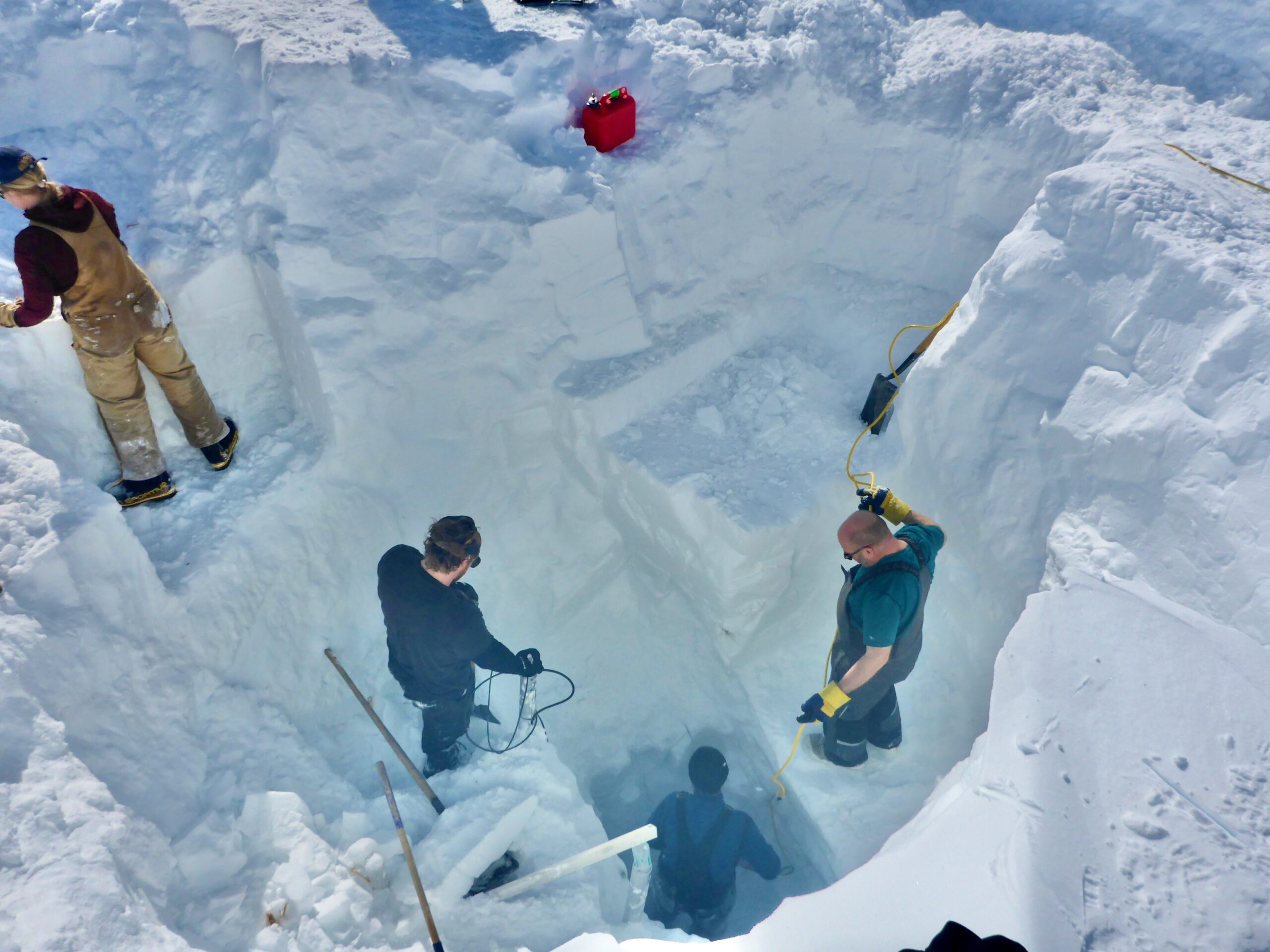 People below ground in a trench looking at the dig progress in the snow .