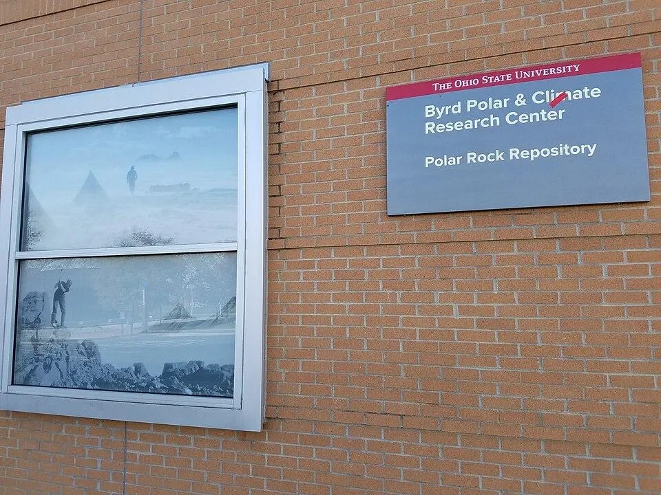 Exterior brick building alongside a window featuring polar-themed photographic imagery of explorers and snowy landscapes.