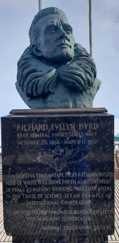 A metal statue on a pedestal with a plaque.