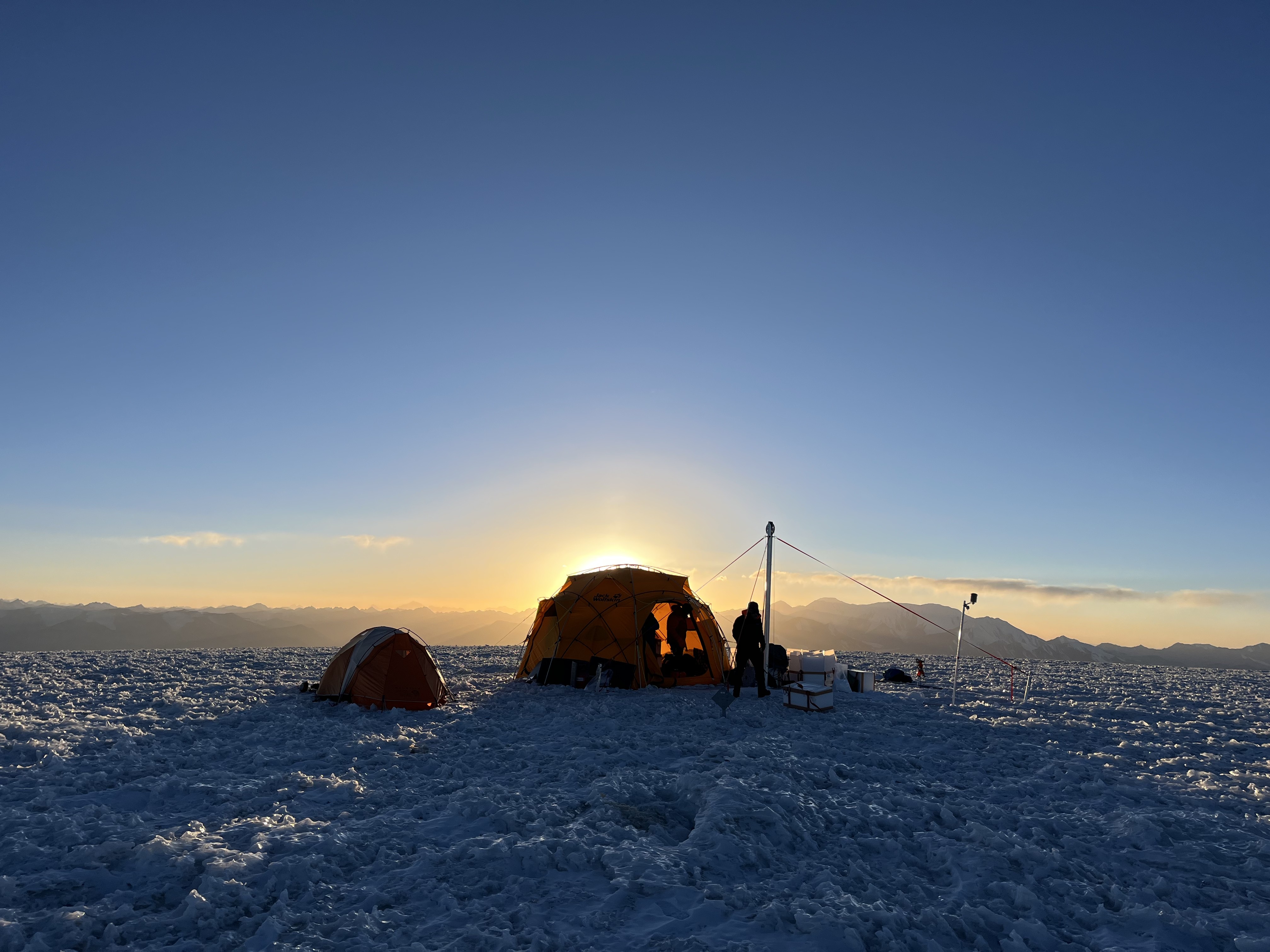 The sun peaks out from behind a basecamp tent 