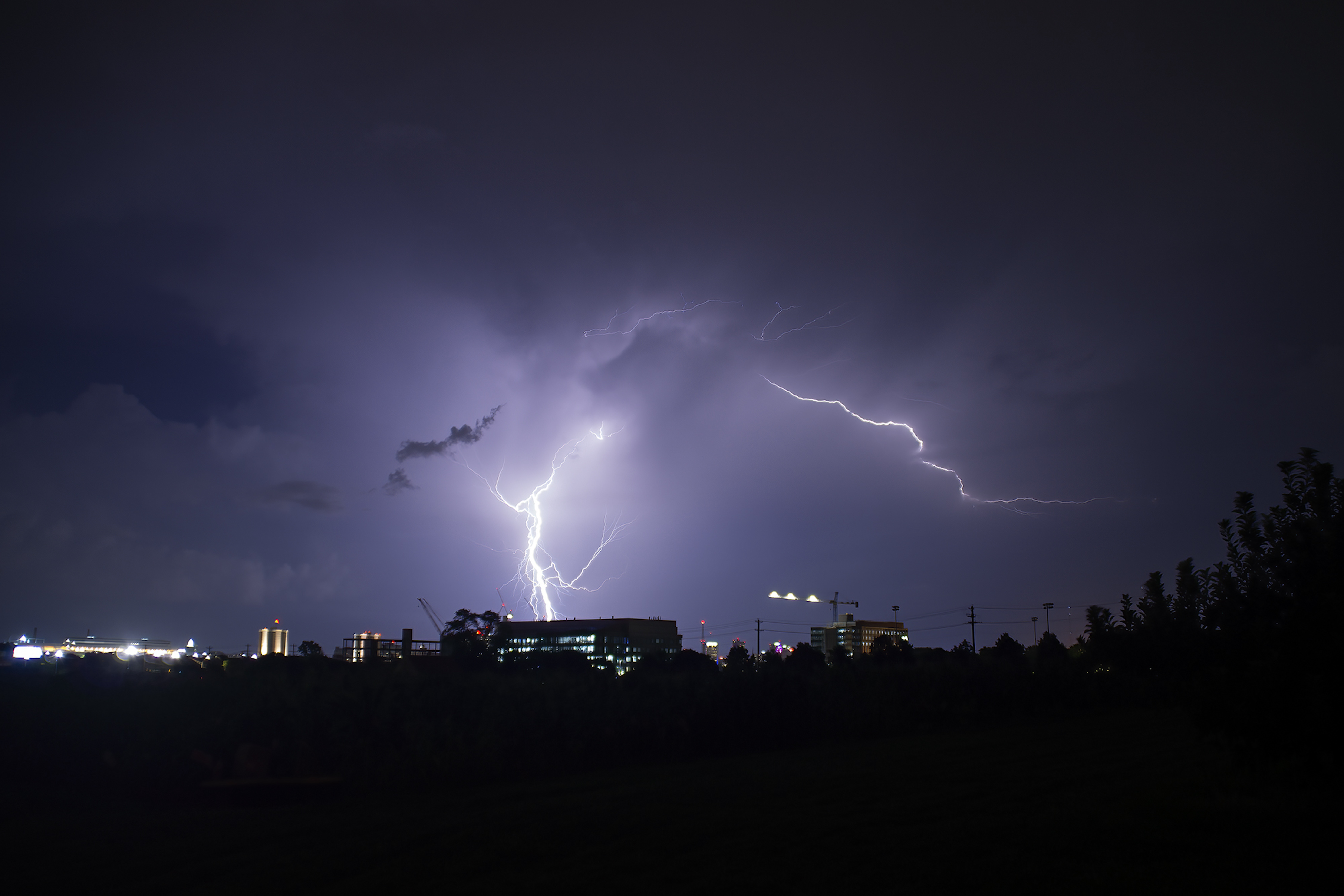 A lightning strike lights the night sky up with a purple color. 