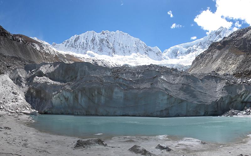 A large glacier positioned behind a small body of water 