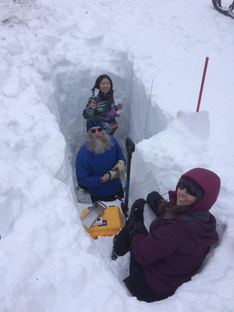 Three people in a large cutout of ice.