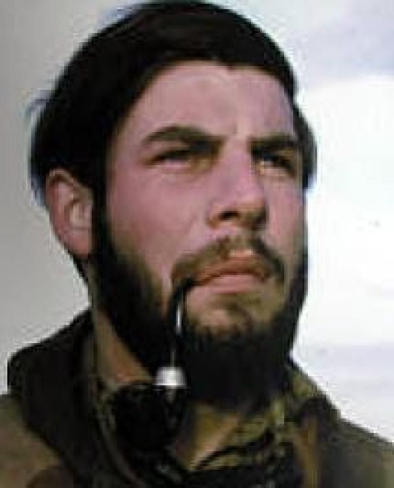 A bearded man smoking a pipe.