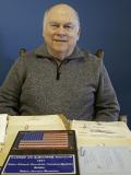 Bob Mayer smiling for a photo while sitting at a table 