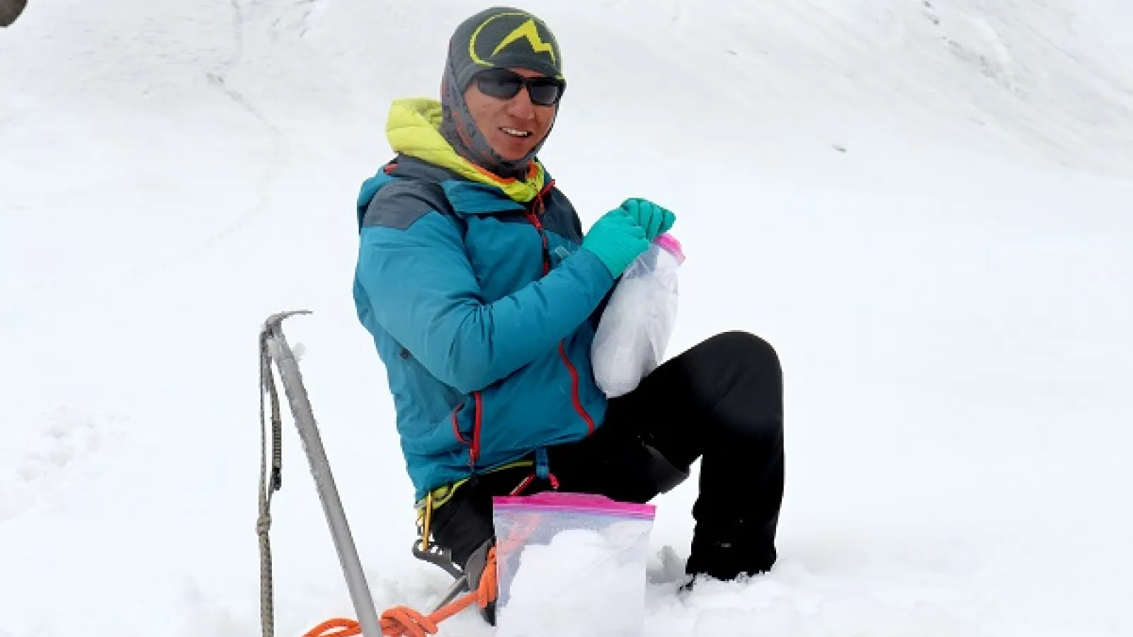 man in snowsuit kneeling in the snow