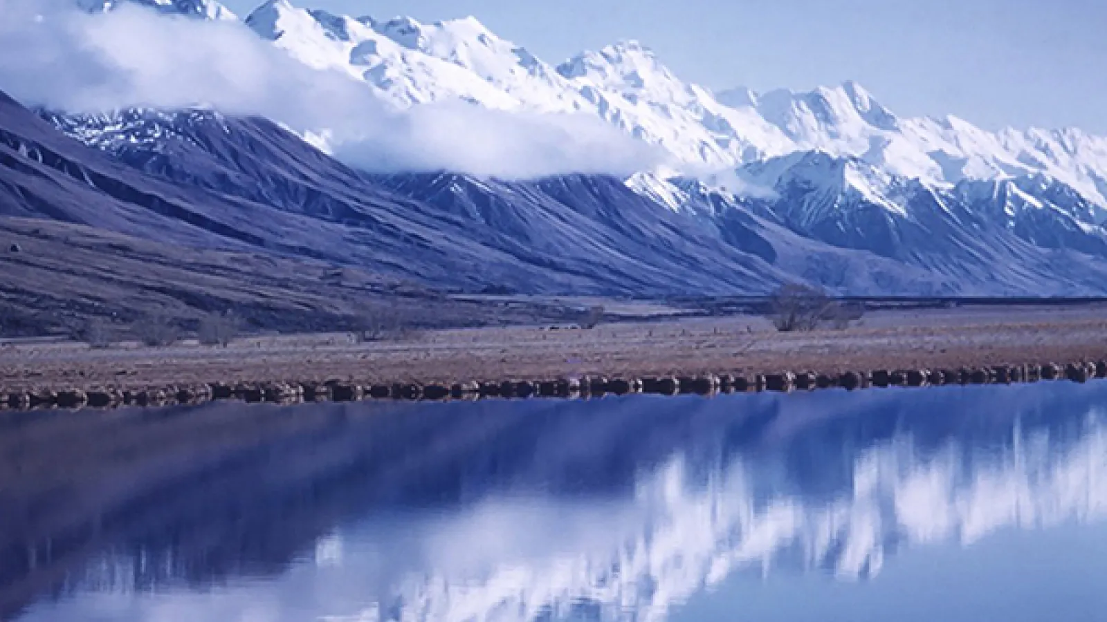 Antarctic mountain range behind a still blue lake 