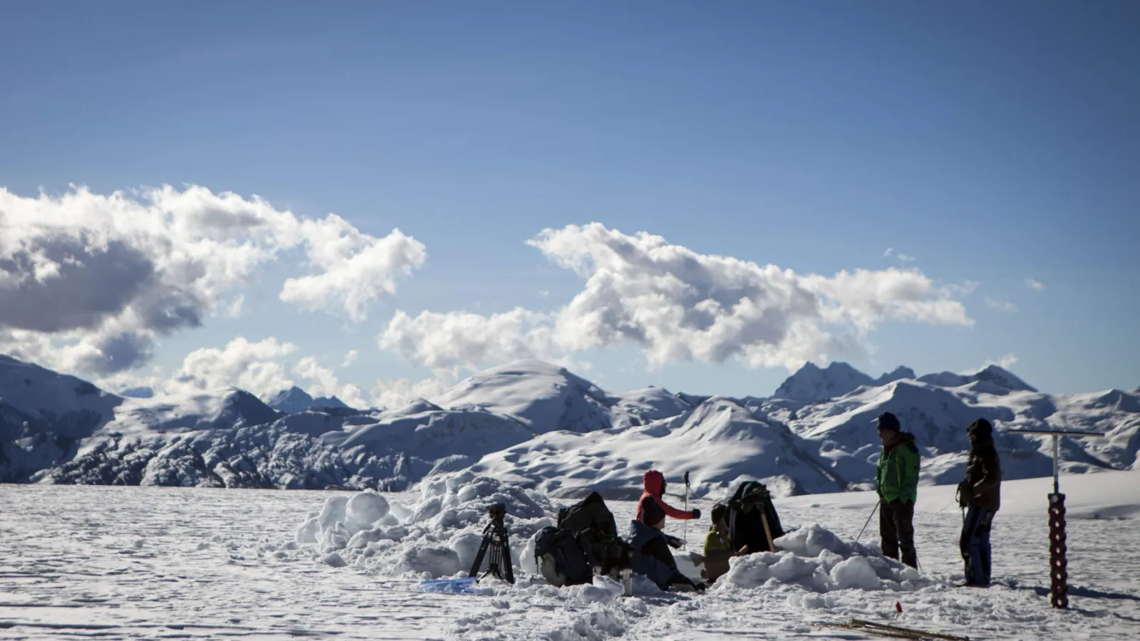 group of people working on a snowy landscape with a snowy mountain in the back 