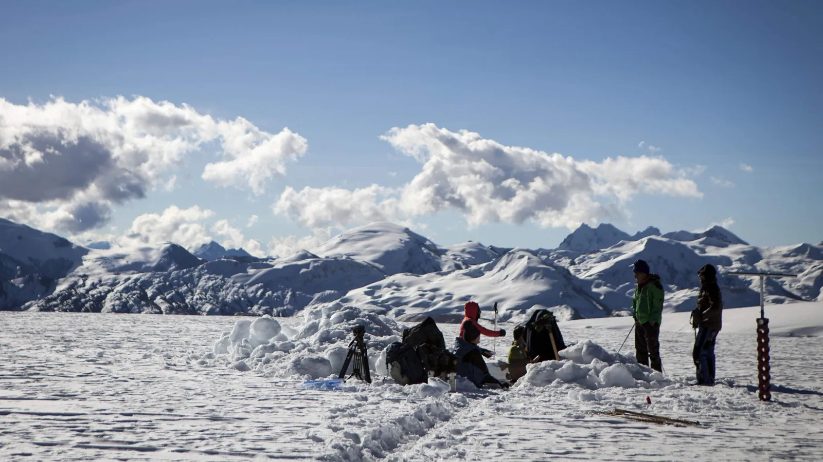 people gathered on a snowy landscape with a snowy mountain in the background 