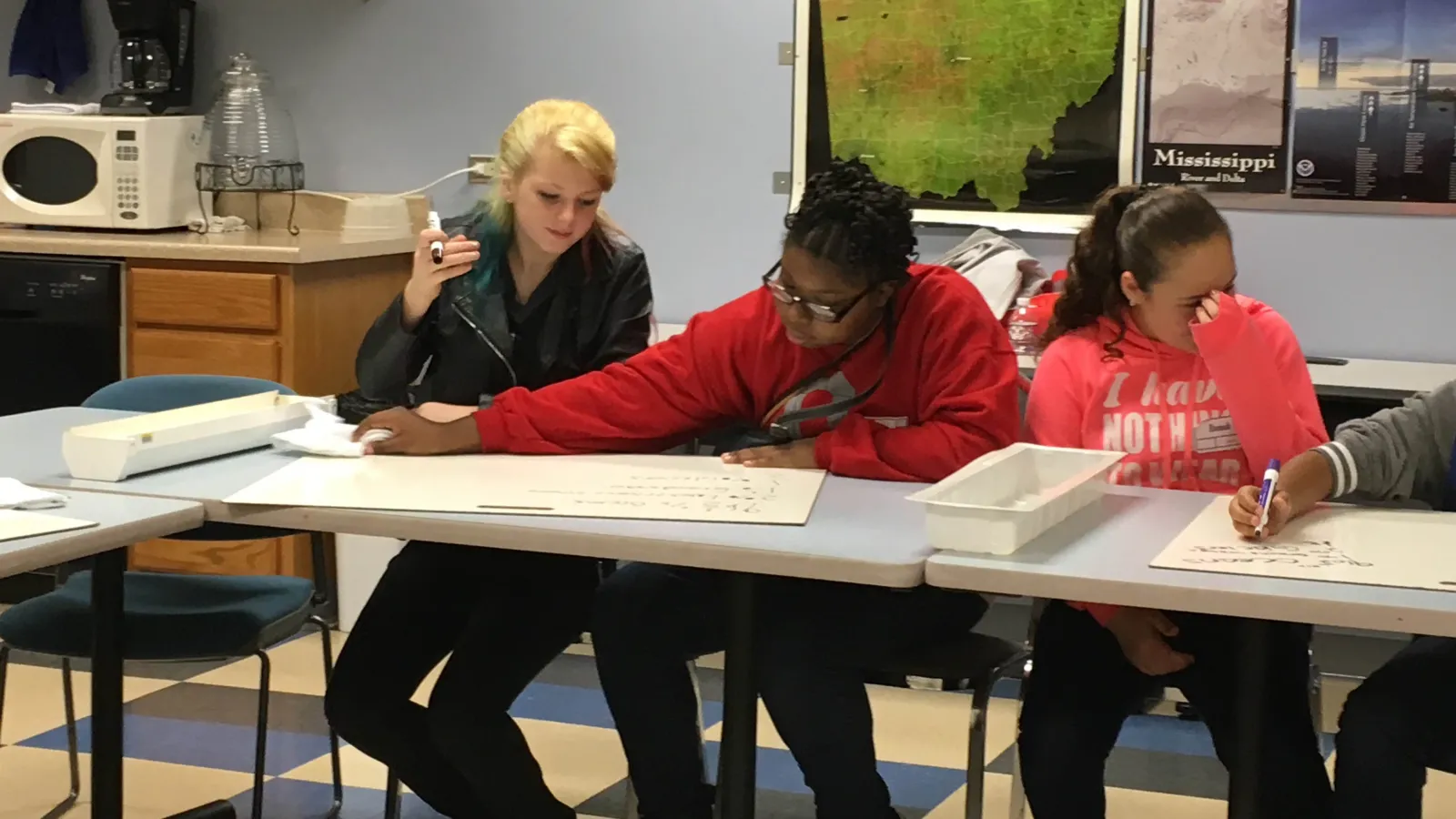three students sitting at a table having a discussion in the Byrd Polar and Climate research center