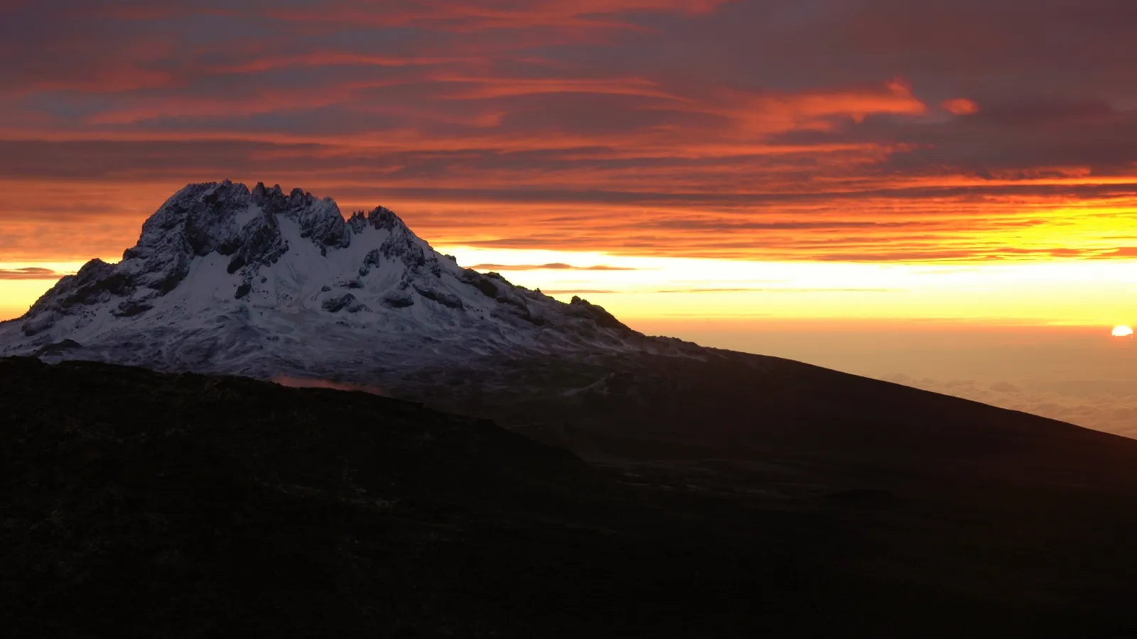 a silhouette of a mountain at dawn 
