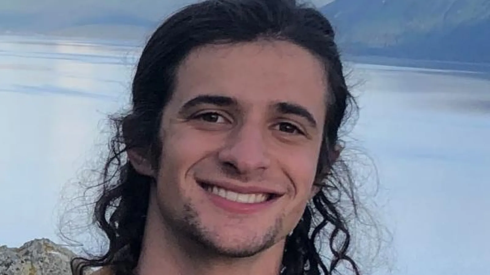 Tal Shutkin smiling in front of landscape with a lake and mountains 