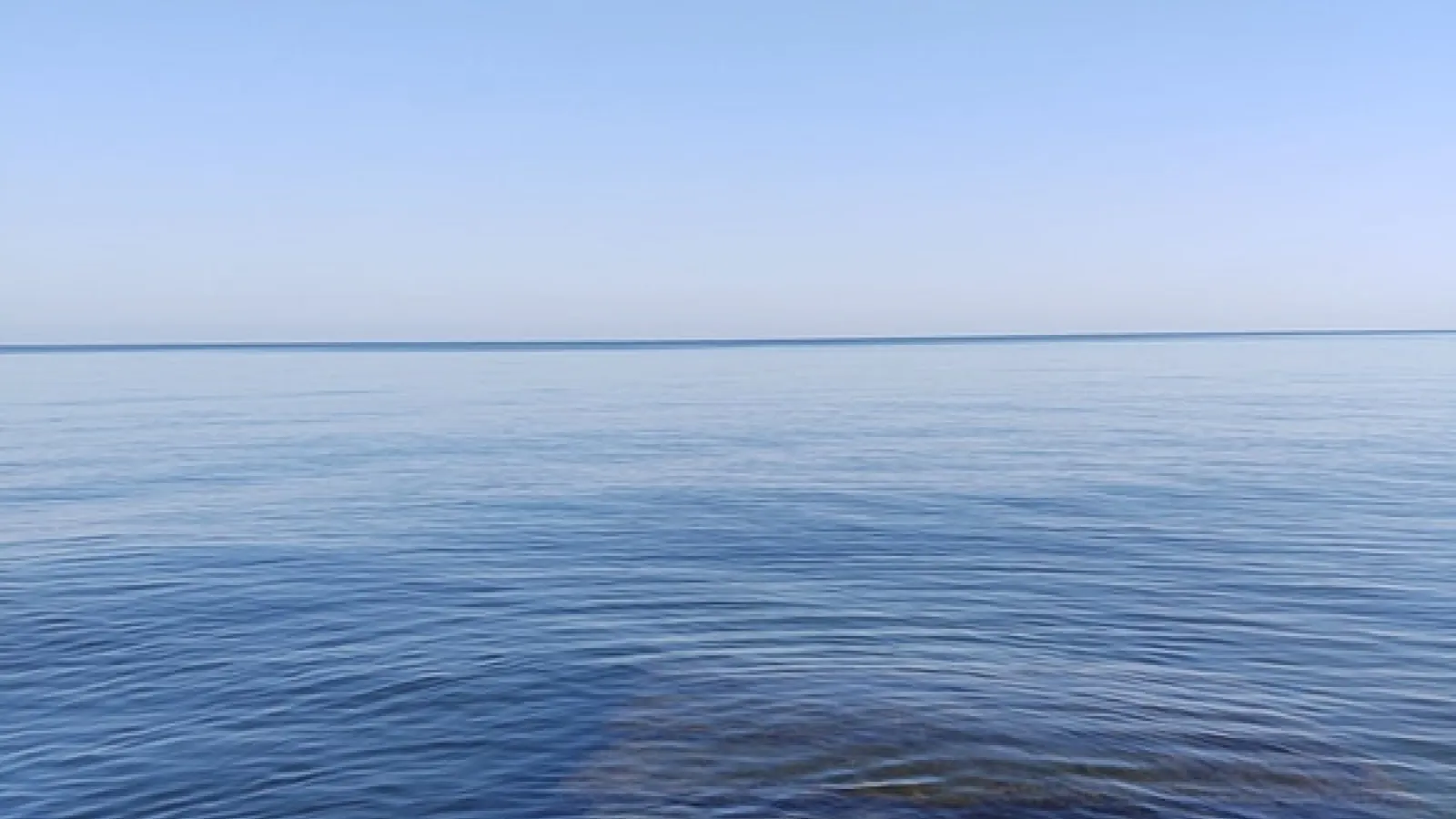 Water from a shallow bedrock area with a blue hazy sky