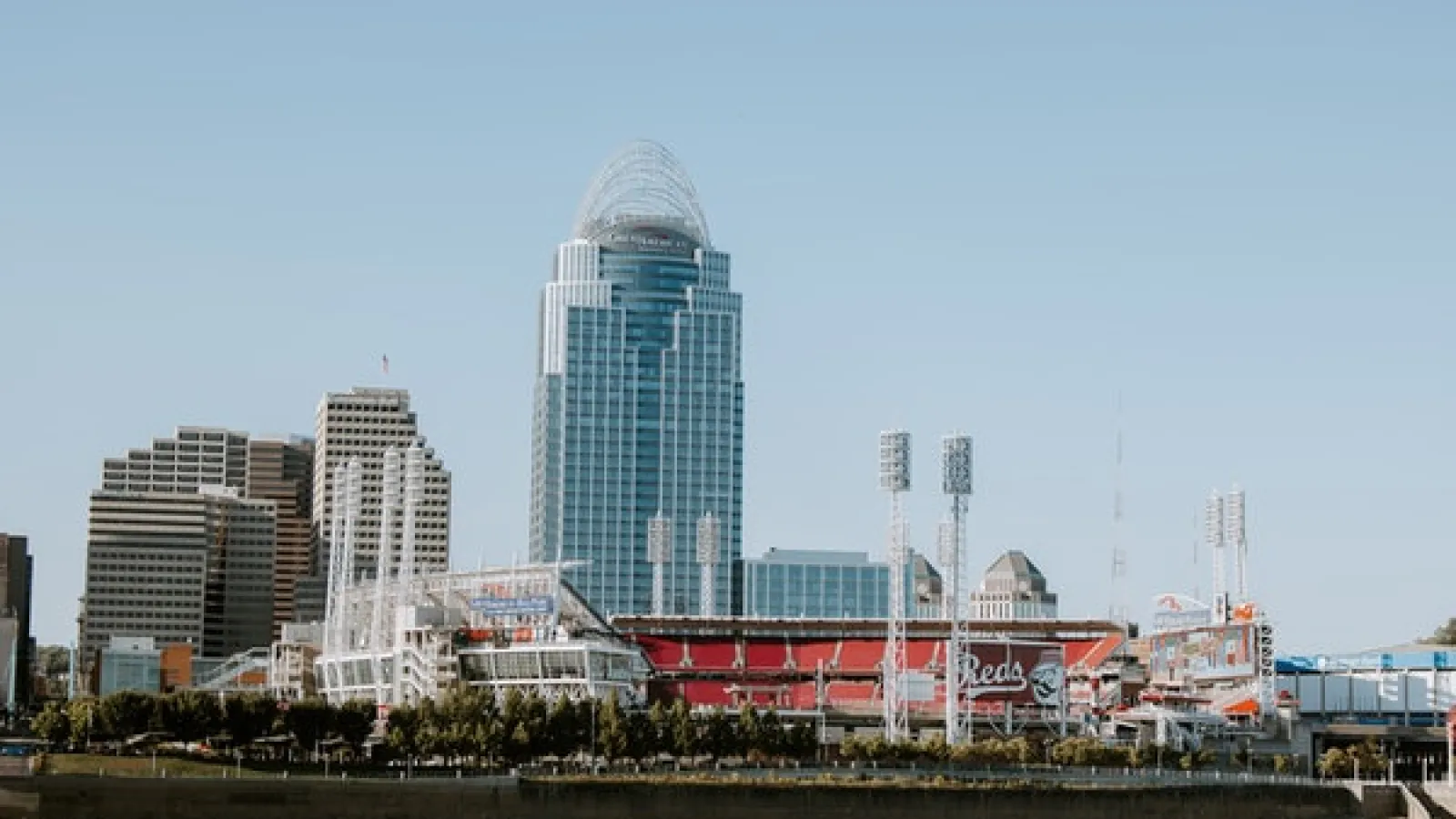 View of downtown Cincinnati during the day with the river, Reds stadium, Great American tower, and other buildings.