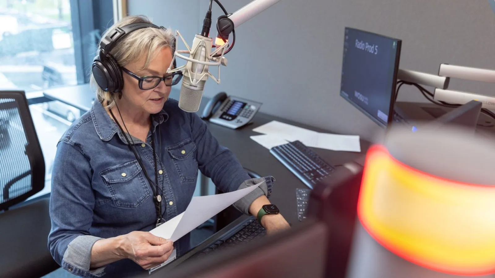 Ann Fisher at her desk making an announcement in microphone