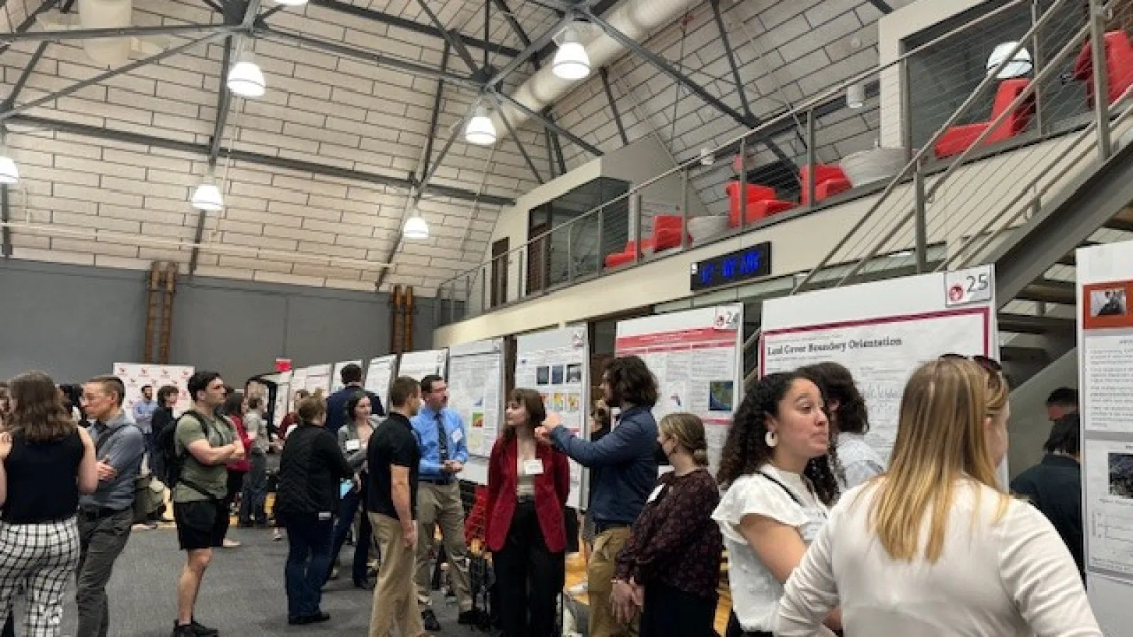 People in a gather hall walking around with posters hanging on boards. 