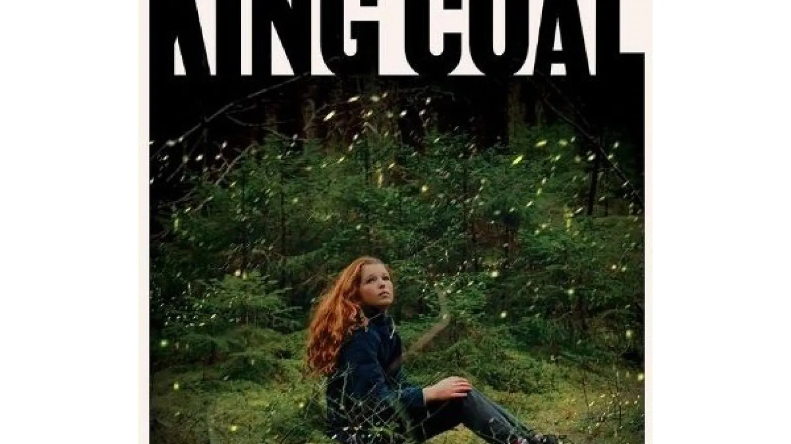 A person sitting on grass in the woods surrounded by shrubs with large text saying King Coal