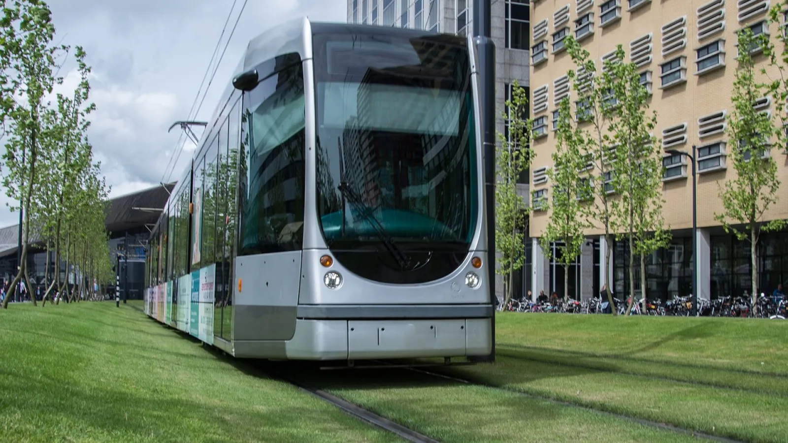 Tram on track in grassy urban environment.