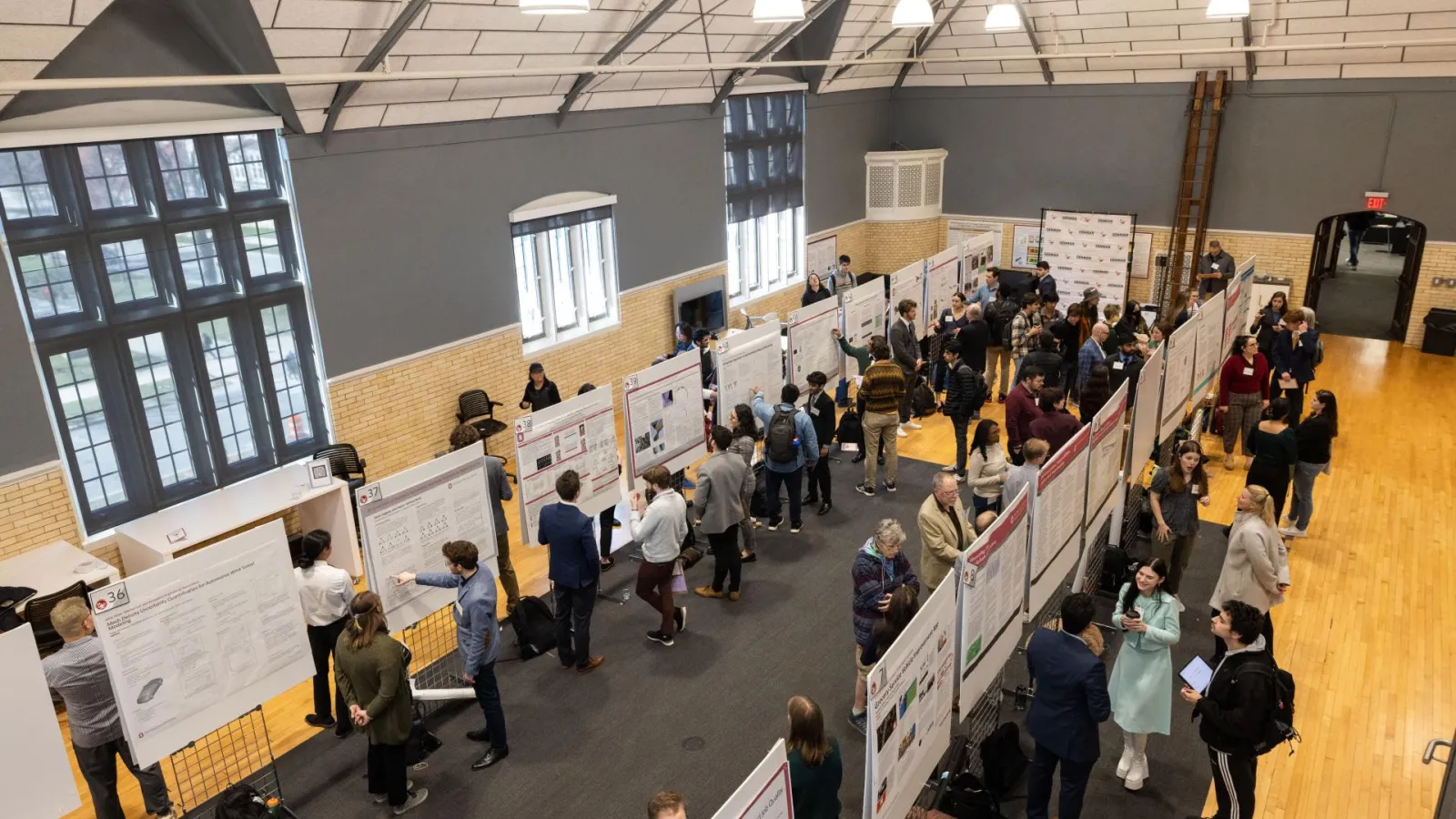 Multiple undergraduate students presenting their research posters at a forum.