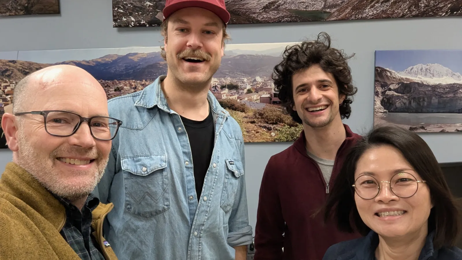 Four people indoors posing for a picture and smiling.