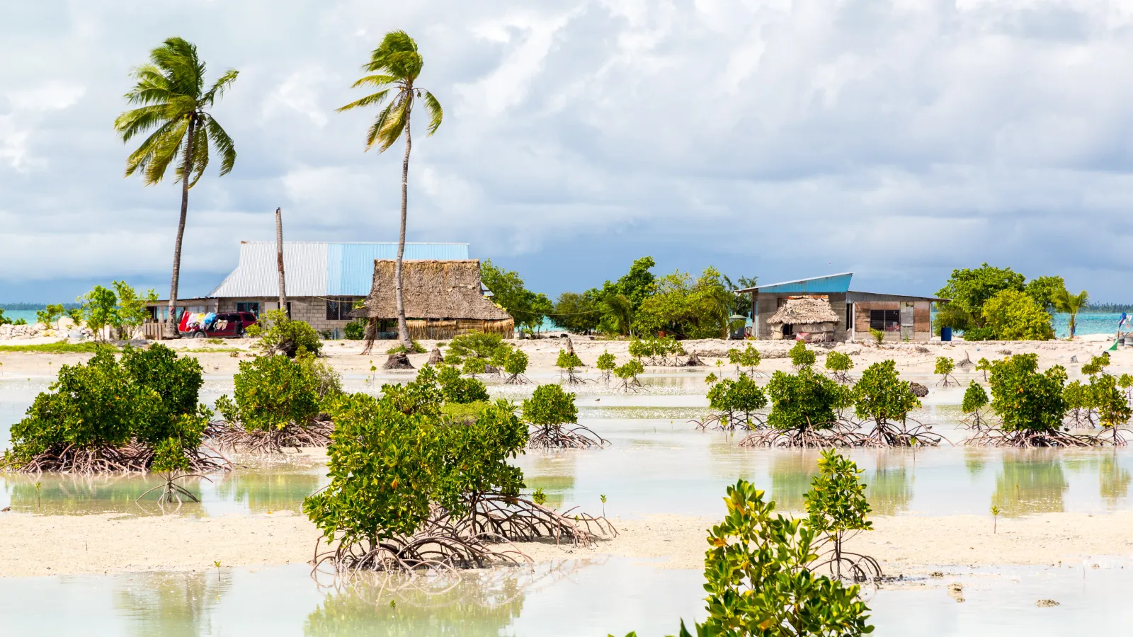 Thatched roof houses. Rural life, a remote paradise island under blue skies and white clouds and palms.