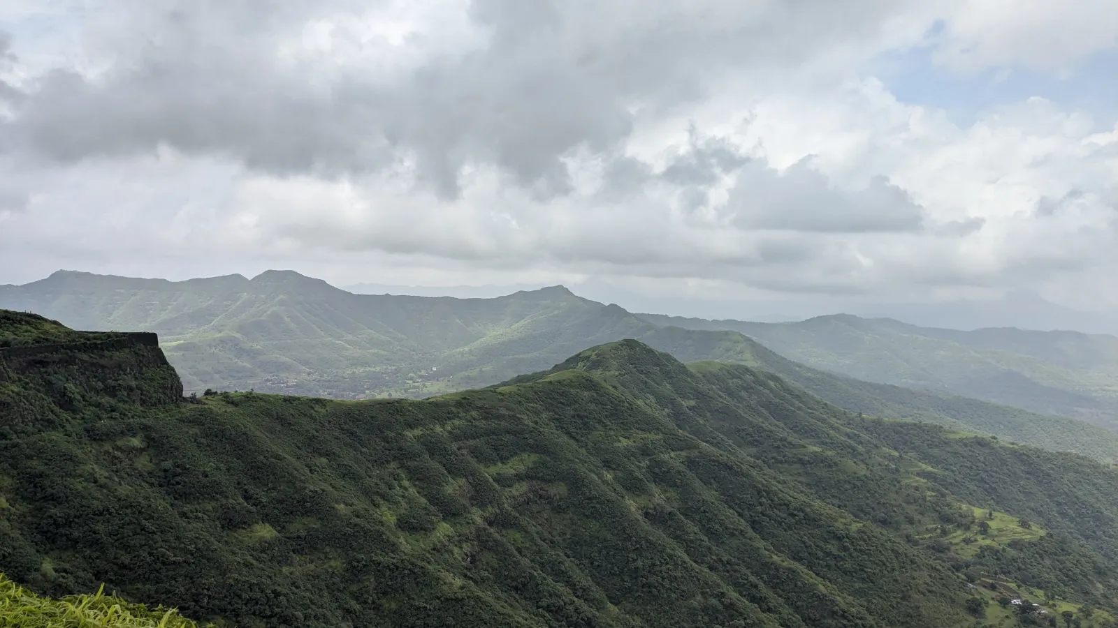 view of green mountains under white clouds at a distance
