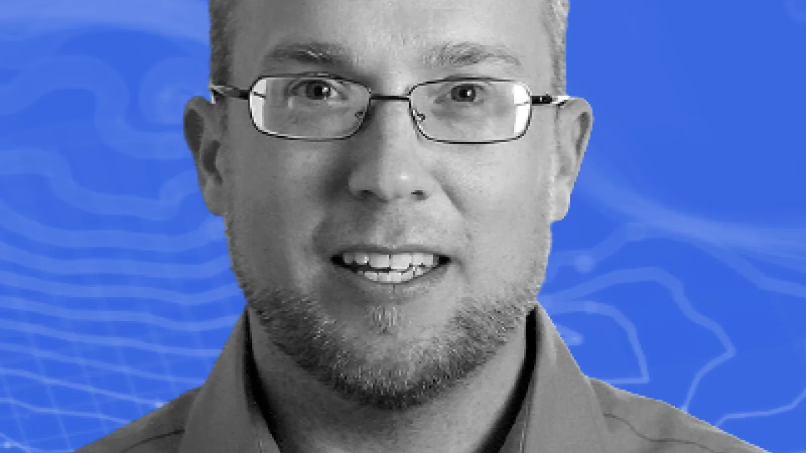 Headshot of a man wearing glasses against a blue patterned background.