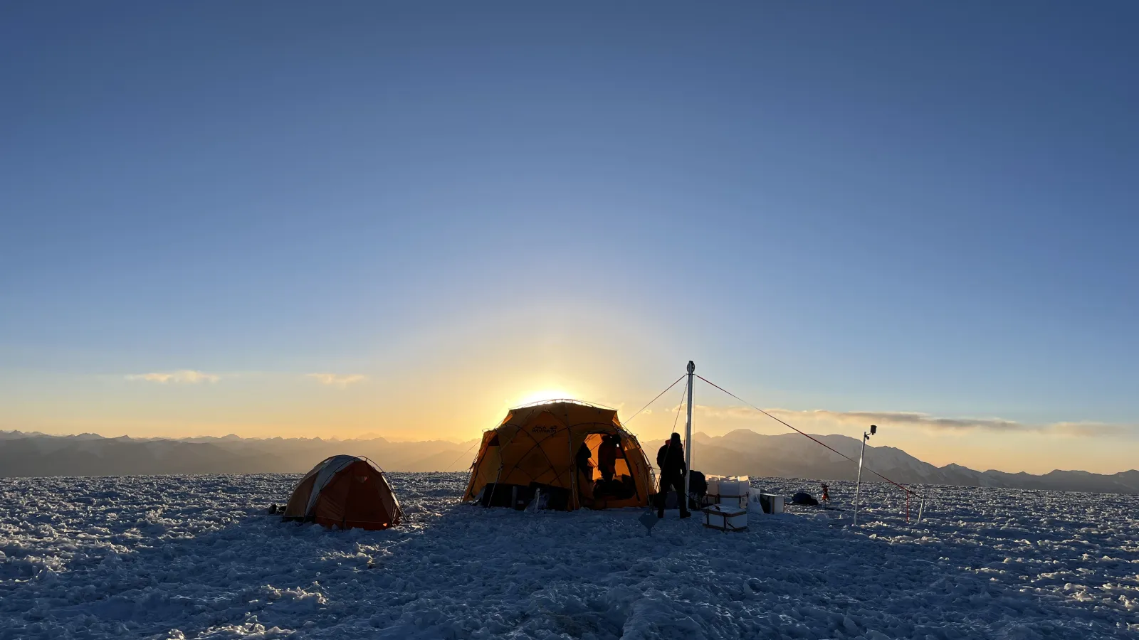 The sun peaks out from behind a basecamp tent 