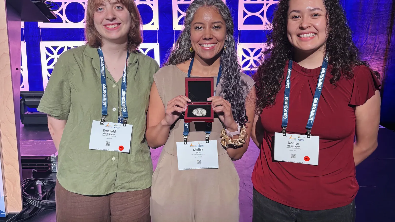 Melisa Diaz standing in the center and smiling holding her F.W. Clarke award