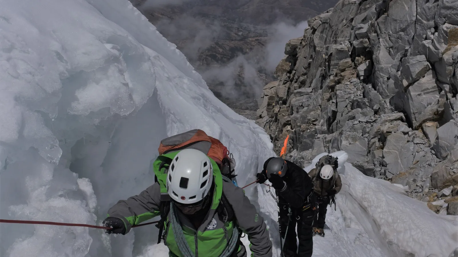 Three mountaineers climbing on ice