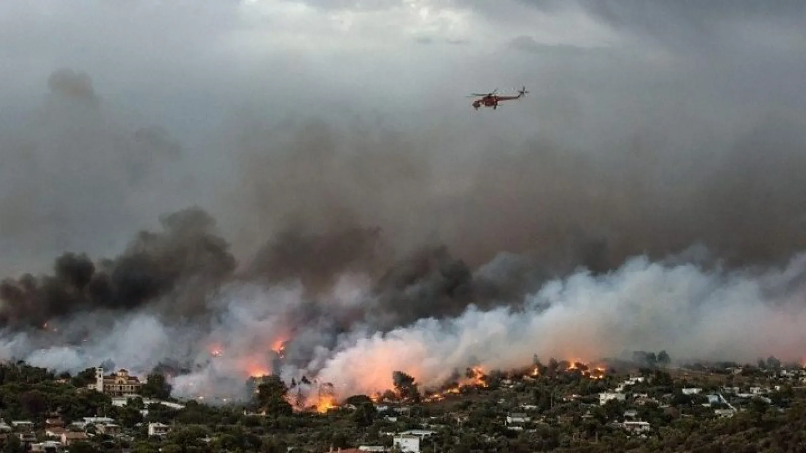 A helicopter flies over smoke from a burning forest