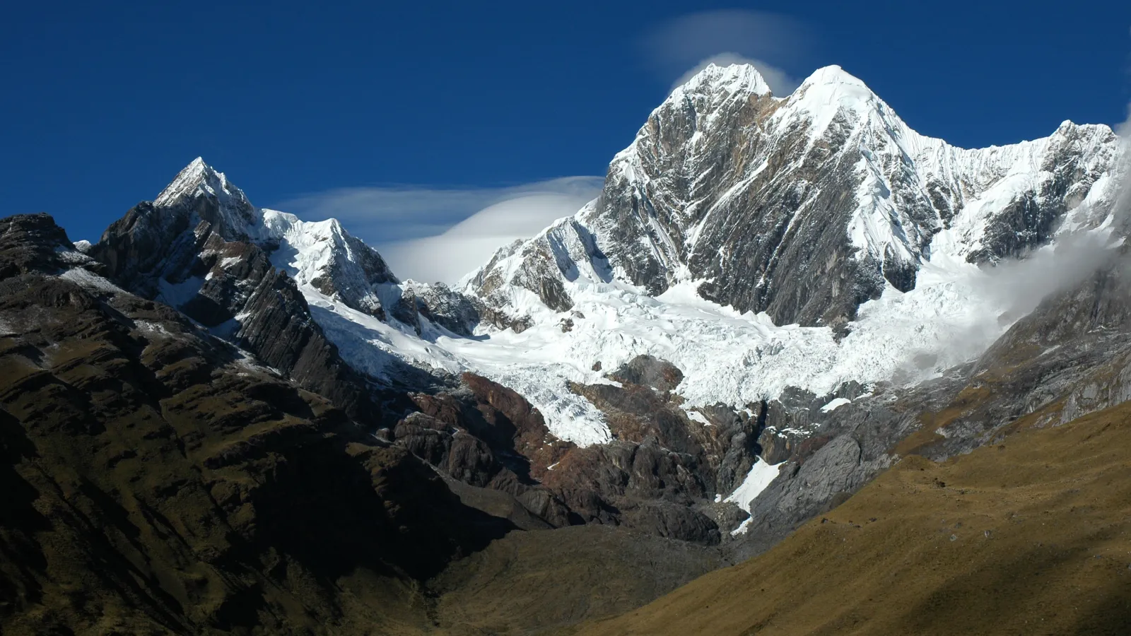 Landscape of mountains with snow covered caps. The sky is a sunny and bright blue