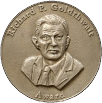Goldthwait Polar Medal. Around the rim of the gold medalion, it reads "Richard P. Goldthwait Award." In the middle are the head and shoulders of a man in a suit with short hair and a wrinkled forehead..