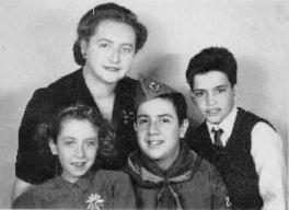 A black and white photo of a mother, two sons, and a daughter. They are all smiling and dressed well.