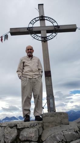 Henry standing at the Top of Innsbrook. There is a large, wooden cross behind him. The clouds are gray and looming overhead.