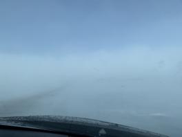 Blowing snow covering the road taken from inside the car front windshield