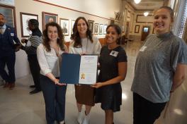 Four women holding a city council certificate
