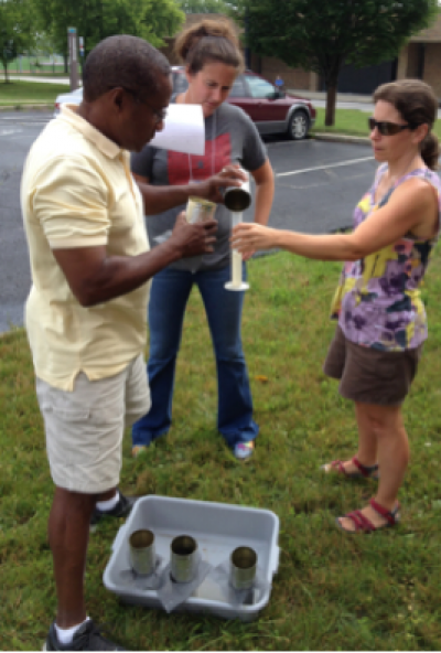 three people conduct a small experiment outside in the grass 