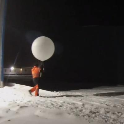 Person in the dark with a white balloon in snow