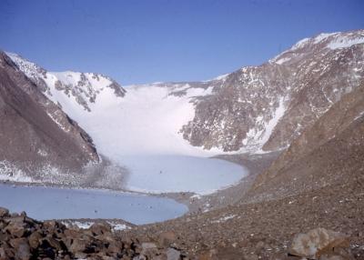 The bowl of a valley surrounded by ice and rock with a pool of water at the bottom