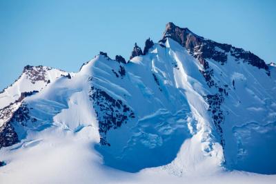 Rocky mountain covered with snow under blue skies.