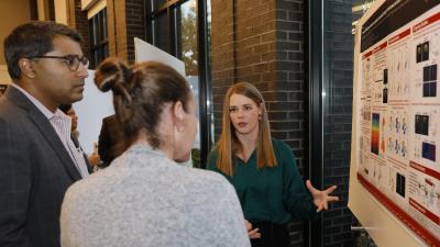 Scientist describing her poster in a crowded site. 