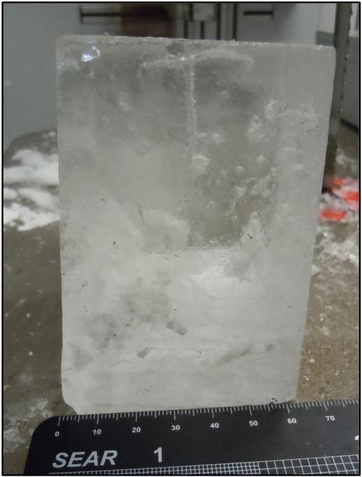 A block of ice on a surface with a ruler in front of it.