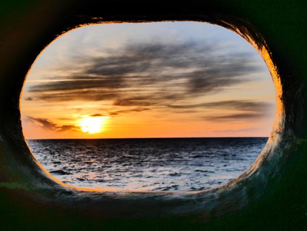 A beautiful view of sunrise over the sea through the hawsehole.