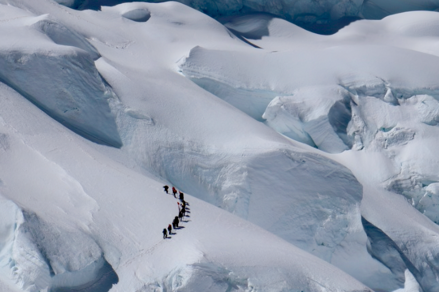A group of researchers hiking Peru’s Nevado Huascarán surrounded by snowy mountains. 